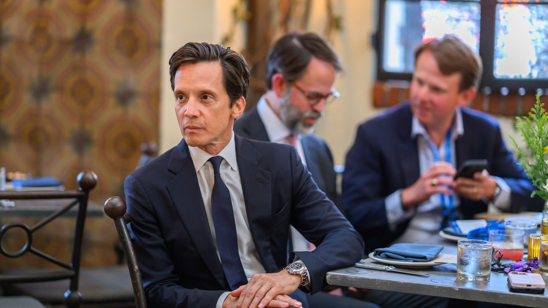 Three businessmen in suits sitting at a conference table during a meeting